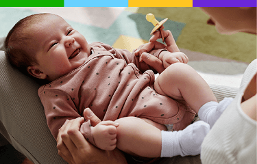 Representación actoral de un bebé con un chupón que sonríe a sus padres