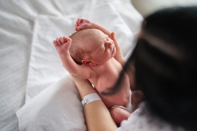 Representación actoral de un bebé en brazos de una madre en un hospital