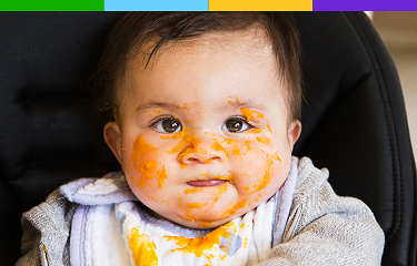 Representación actoral de un bebé de 3 a 9 meses en brazos de sus padres al aire libre